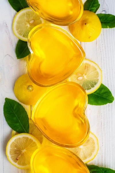 흰색 나무 배경, 상단보기, 수직 구성에 하트 모양의 유리에 노란색 레몬 젤리 — 스톡 사진