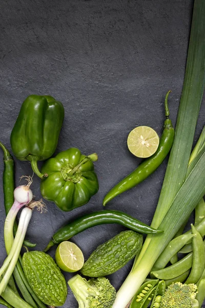 Concepto de comida ecológica, vista superior, composición vertical. Verduras verdes crudas como pimiento verde, fugas, cebolla primaveral, guisantes, brócoli, chile verde lima . — Foto de Stock