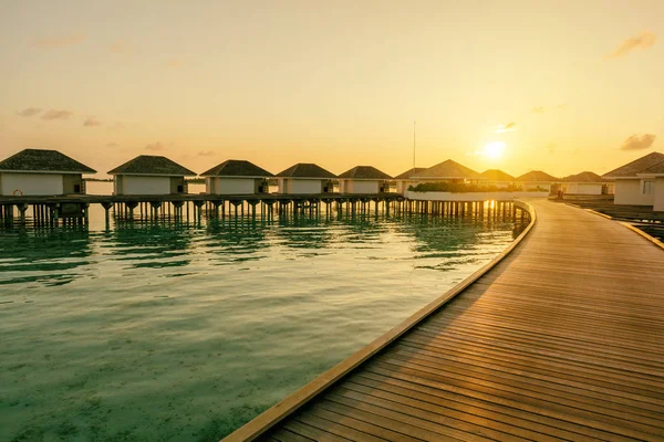 Muelle de madera y línea de villas tropicales al amanecer, Maldivas — Foto de Stock