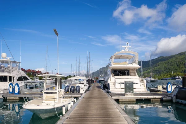 Luxuosos iates e barcos e longo cais de madeira no dia ensolarado de verão na marina de Eden Island, Mahe, Seychelles — Fotografia de Stock