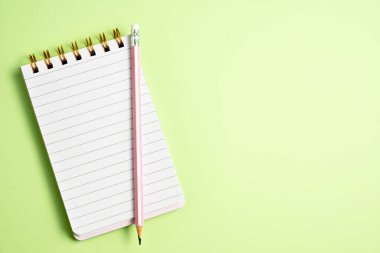 Pastel yeşil sırtında pembe kalemle boş defterin üst görünümü