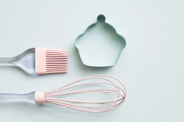 Pink silicone cooking brush, whisk and small metal cookie cutter — Stock Photo, Image