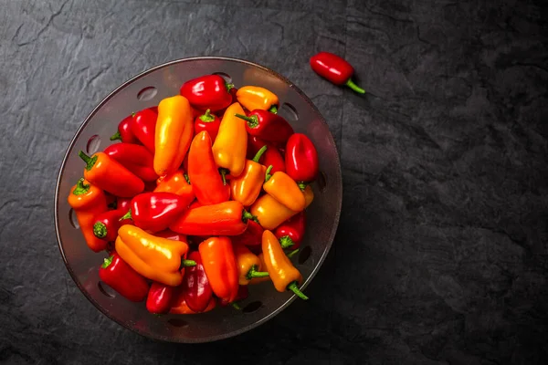 Colourful  mini bell peppers in glass bowl on dark background, t — Stock Photo, Image