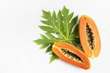 Olgun taze kesilmiş papaya meyvesi beyaz arka planda yeşil papaya yaprağı, düz yatış, kopyalama alanı 