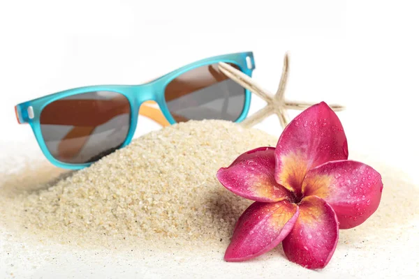 青いサングラス 白い夏休みのコンセプトの砂とFrangipani花 — ストック写真