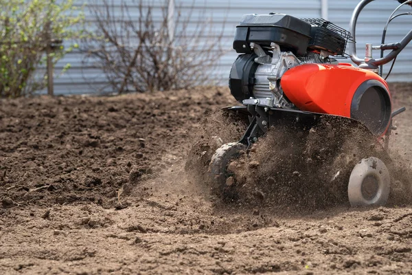 Çiftçi toprağı kazar, toprak parçaları ekicinin altından uçar.