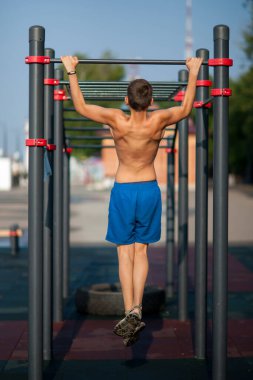 Genç adam kendini oyun parkının yatay çubuğuna çekti..