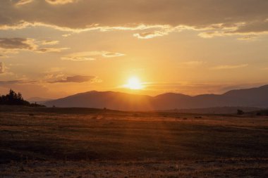 Dağların eteğindeki tarlada güzel bir gün batımı.