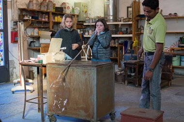 Murano, İtalya - 09 Ekim, 2013: çırak bir cam heykel bir gösterisi sırasında üfleme ünlü Murano cam fabrikasında bir ustanın, çocuk cam üfleme katılmak. 