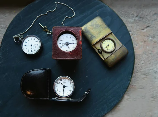 a collection of precious vintage old clocks and watches on a green wooden background, all from the past century, demonstrating that time is relative and antique items are back and fashion