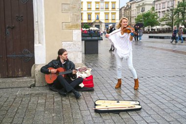 Krakow, Polonya - 27 Ekim, 2017: sokak müzisyenleri, bir adam gitarist ve arcade alışveriş Sukiennice yakınındaki şehir merkezinde bir kadın ogrenci modern ve klasik müzik güzel konser