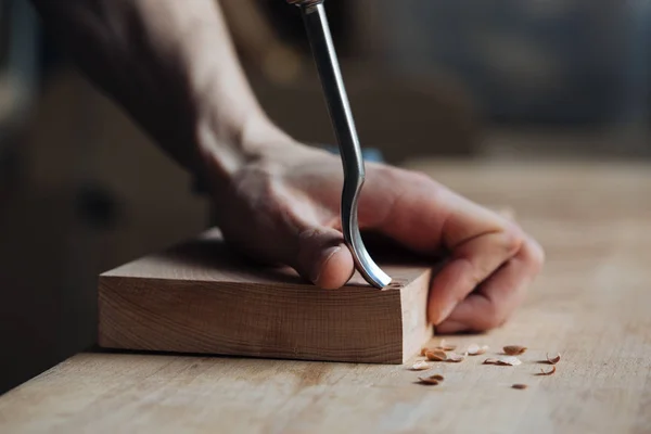 Tallado en madera, las manos del maestro trabajan con una superficie de madera, un profesional hace artesanía de madera — Foto de Stock