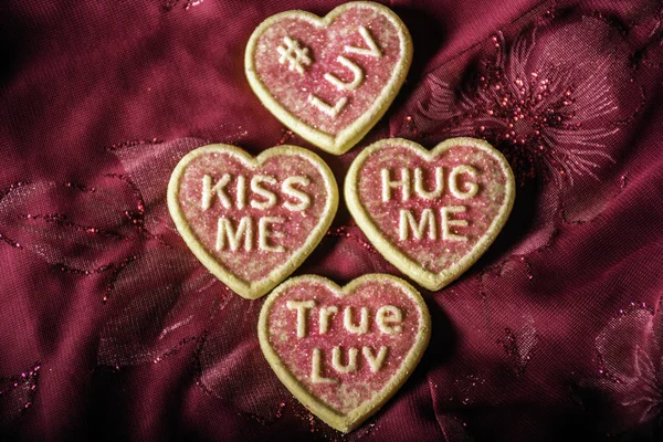 four heart shaped conversation red sugar cookies on red cloth background