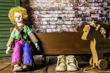 antika ahşap beşik yanında kırmızı sallanan sandalye üzerinde oturan eski bebek Bebek Patiği ve ahşap oyuncak at Yeşil perde ve tuğla duvar arka plana sahip ahşap zemin üzerinde yıpranmış