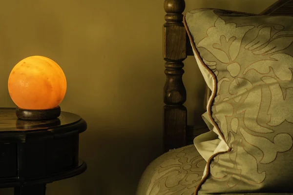 Himalayan salt lamp on night stand next to bed and large pillow