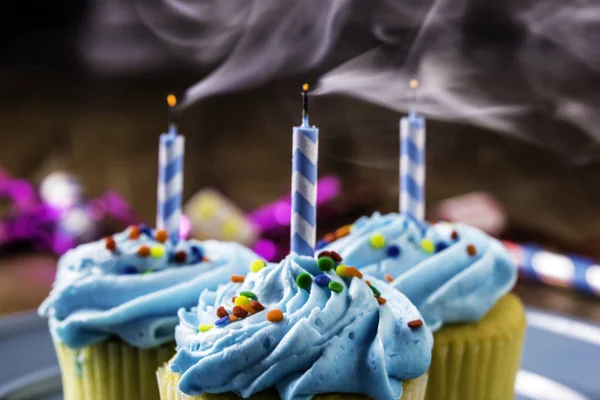 Drei Gelbe Cupcakes Mit Blauen Zuckergläsern Und Kerzen Auf Blauem — Stockfoto