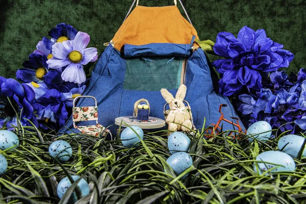 miniature stuffed rabbit in front of blue camping tent in field of green grass and blue Easter eggs with blue flowered background