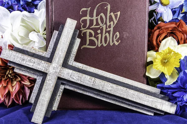 Stary Drewniany Krzyż Przed Dużą Biblią Niebiesko Otoczony Wiosennymi Kwiatami — Zdjęcie stockowe