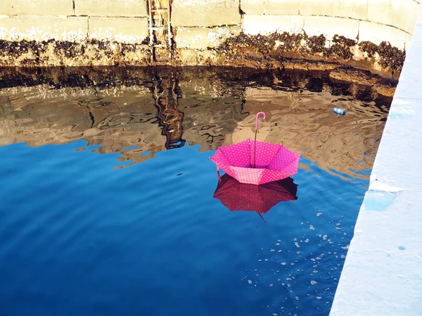 Ombrello rovesciato rosso galleggiante sulla superficie dell'acqua — Foto Stock