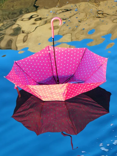 Красный перевернутый зонтик, плавающий на поверхности воды — стоковое фото