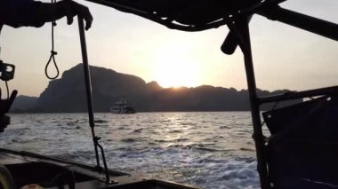 Taylandlı bir adam uzun kuyruklu bir tekne kullanıyor ve şafak vakti Tayland 'da denize açılıyor.