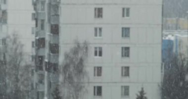 Kış mevsiminde şehirde kar yağarken, arka planda Rus şehrinde binalar var.