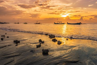 Kuta sahilinde renkli bulutlar ve teknelerle Bali 'de güzel bir gün batımı.