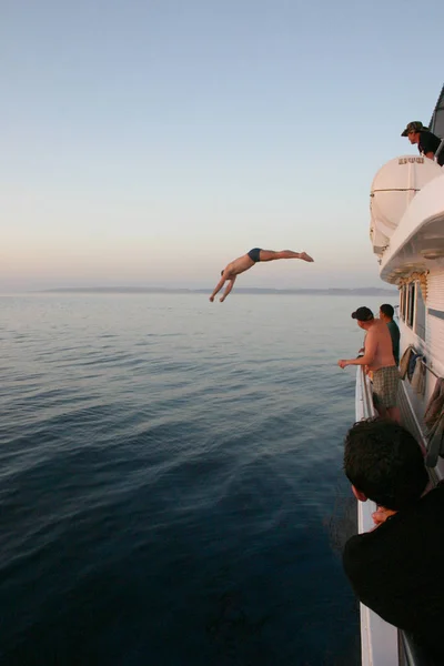 Homem mergulha na água de um barco — Fotografia de Stock