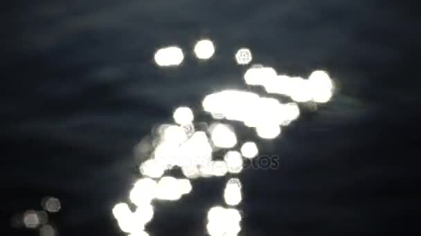 Vue déconcentrée d'une surface d'eau ondulée avec un beau bokeh d'éblouissements du soleil qui sont réfléchis par le lac 