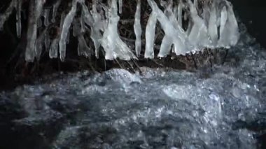 Donmuş akışı. Karlı ve buzlu suda taş. Icicle'ı feryat şelale, taşlı ve karlı akışı banka düşmüş dalları ile. 