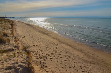 Büyük bir gölün kıyısındaki kum tepeleri, sudaki güneşin yansıması. Indiana Dunes Ulusal Lakeshore, Usa