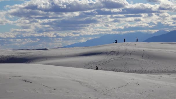 人々は白い雲の背景に砂漠の風景の中に白い石膏の砂の上を歩く 白砂国立記念碑で砂丘 ニューメキシコ州 アメリカ — ストック動画