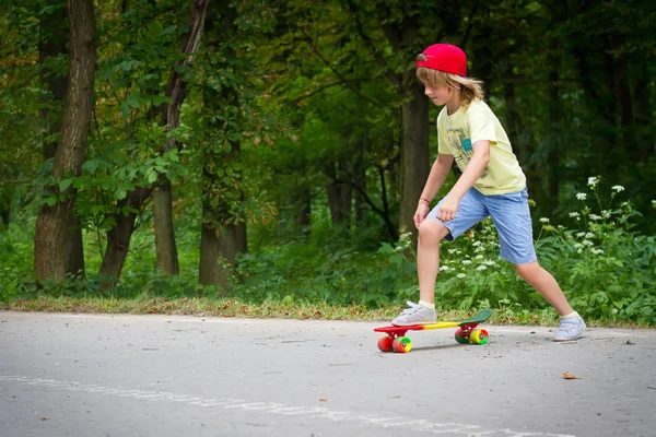 Young boy learning to ride skateboard in the suburb street having fun. — Stock Photo, Image