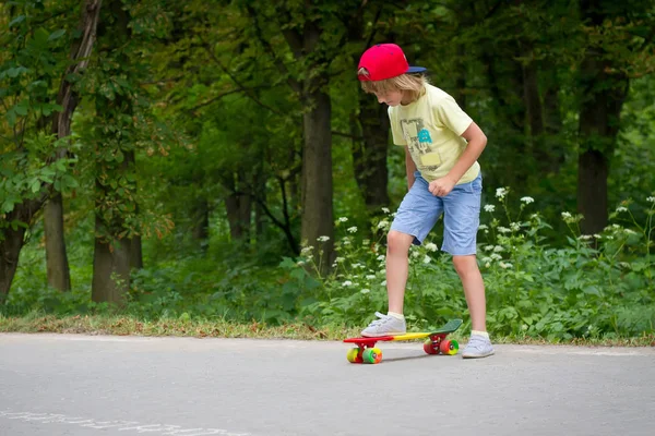 Mladý chlapec, naučit se jezdit na skateboardu v předměstí ulici baví. — Stock fotografie
