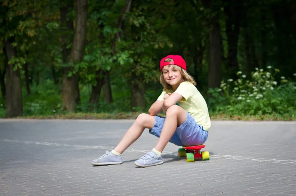 Jovem homem bonito sentado em um skate — Fotografia de Stock