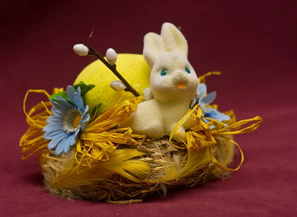 Niedlicher weißer Hase sitzt in einem Korb mit Blumen und bunten Ostereiern — Stockfoto