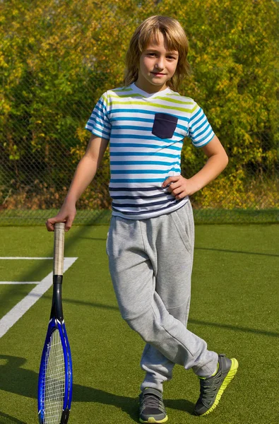 Chłopiec stojący z rakiety tenis i piłkę na boisku — Zdjęcie stockowe