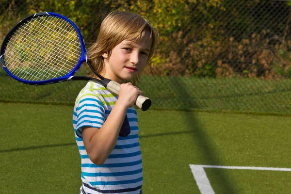 Menino de pé com raquete de tênis e bola na quadra — Fotografia de Stock