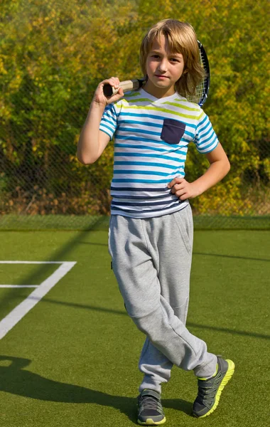 Menino de pé com raquete de tênis e bola na quadra — Fotografia de Stock