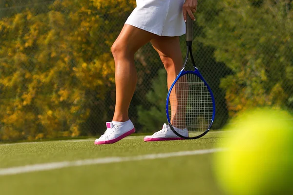 Pelota de tenis en la cancha de tenis con el jugador en el fondo — Foto de Stock