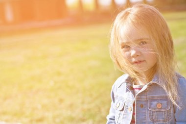 Jeans yeşil bir arka plan üzerinde dağınık saçlı güzel sevimli küçük kız