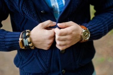 Moda portre genç işadamı yakışıklı modeli adamın elleri, çelik saatler, gri kot pantolon ve bilezikler üzerinde aksesuarları ile rahat bez elbiseli