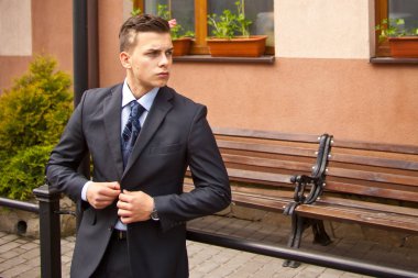 Ofiste çalışmak için sabah gidiş caddenin üzerinde yürüyen yakışıklı genç iş adamı. Genç profesyonel, kentsel yaşam tarzı