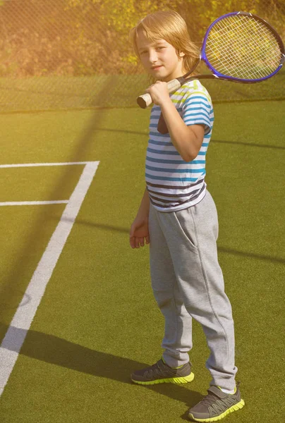Menino de pé com raquete de tênis e bola na quadra — Fotografia de Stock