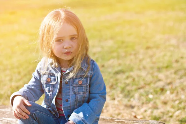 Красива чарівна маленька дівчинка в джинсах зі зневіреним волоссям на фоні зеленого — стокове фото