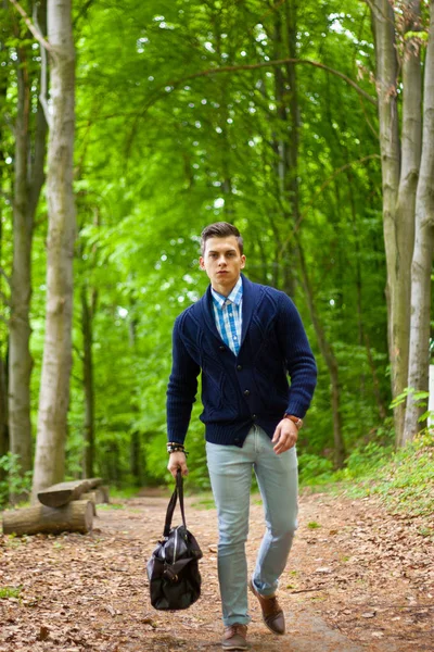 Picture of a young fashion man strolling outdoor with a bag in his hand — Stock Photo, Image