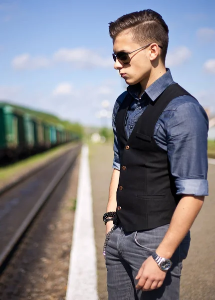Przystojny młody człowiek ubrany casual i okulary przeciwsłoneczne, stojący na zewnątrz — Zdjęcie stockowe