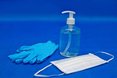 Antiseptik şişe, lateks eldivenler, mavi arka planda yüz maskesi, koronavirüs önleme için.