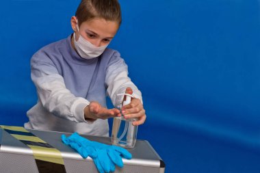 Coronavirus Samokartin. Ön planda bir şişe dezenfektan jeli ve lastik eldivenli adam ellerini yıkamaya hazırlanıyor..