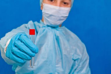 Mavi arka planda test tüpü tutan bir kadın doktor. Coronavirus testi